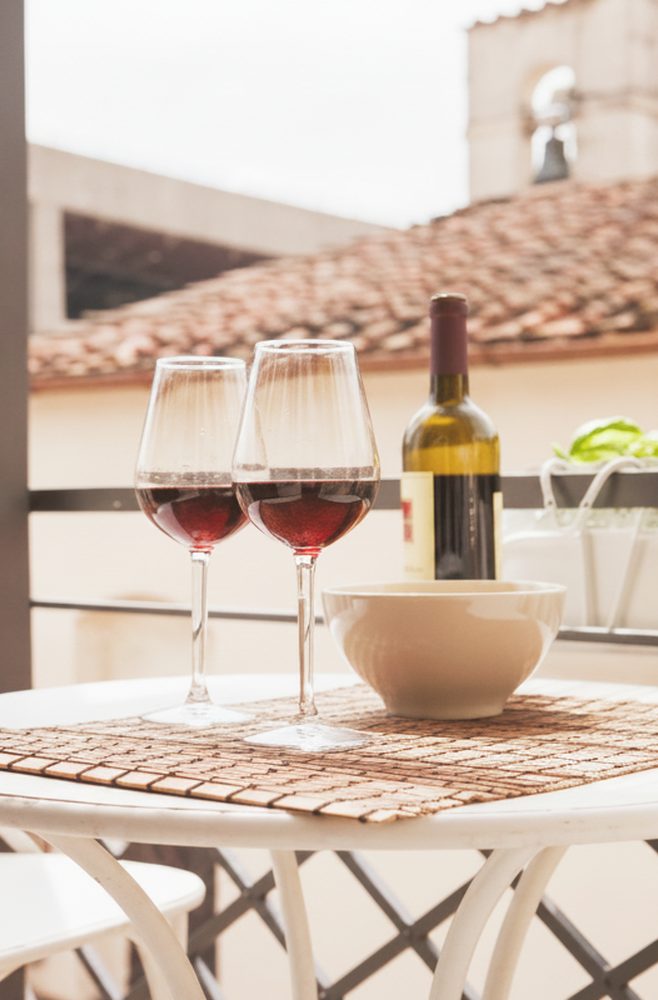 Due calici di vino rosso sul tavolino del balcone, con i tetti di Firenze sullo sfondo