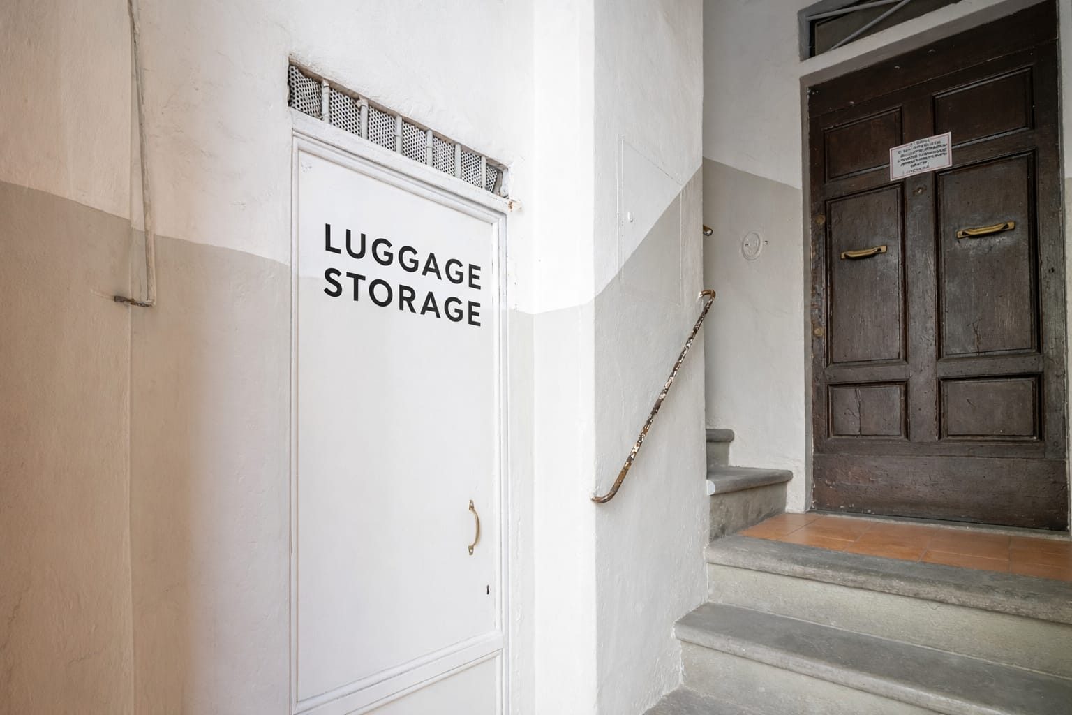 La porta del deposito bagagli con la scritta Luggage Storage, all'ingresso del palazzo accanto alle scale